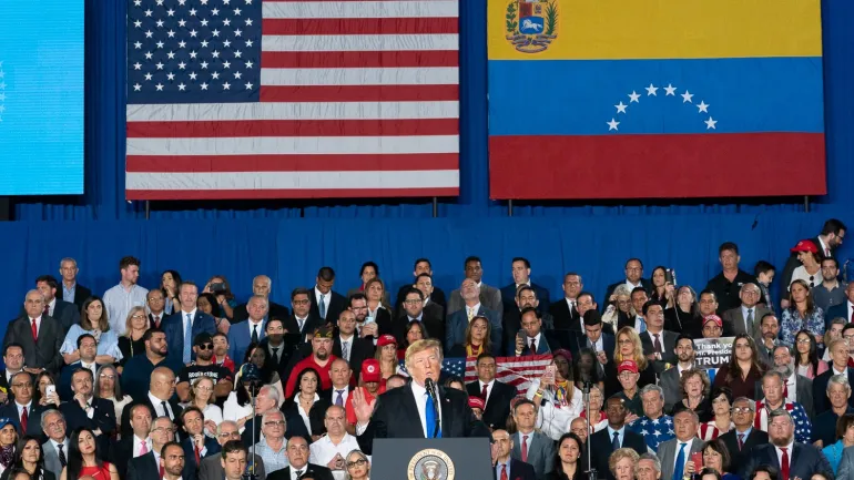 Donald Trump pronunciando un discurso con las banderas de Estados Unidos y Venezuela de fondo